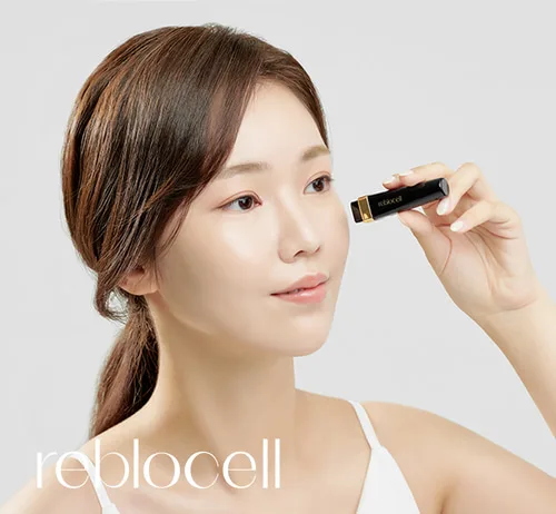 The image depicts a Korean woman in her 30's that is facing the left. The woman has dark brown-black hair that is long and tied in a knot. The woman has very clear and white complexion without any blemishes. The model is wearing a white tanktop. The image only displays the model's shoulders and face. The model is holding a Reblocell MTS Needle Shot with her left hand as if to instruct the viewer how to use the product. In the bottom right corner of the image, the word "reblocell" is written in large, white lowercase font | AS3 Med Spa
